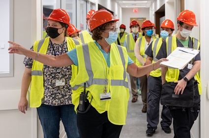 An employee with safety gear and a walkie-talkie leads others on a tour of the new Pavilion building.